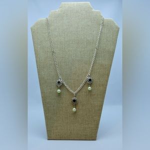 A silver tone chain with three delicate pendants and beads.